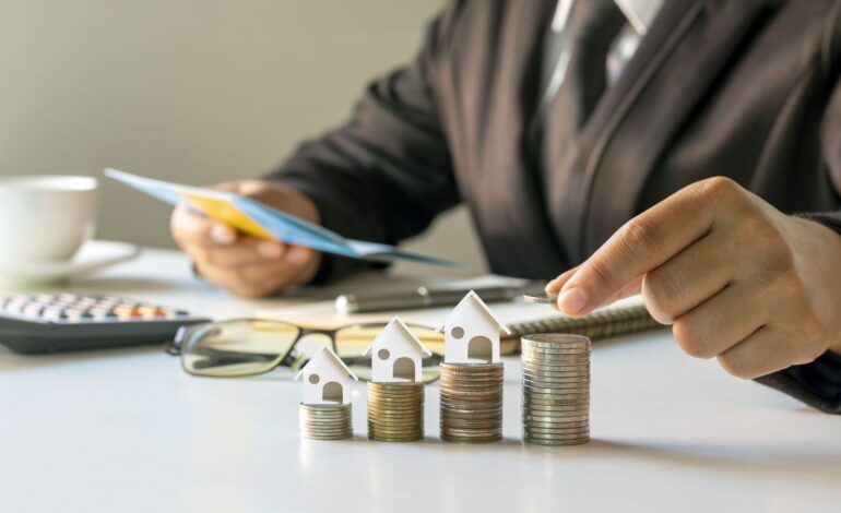 Biznesmen kładący monety na stosie monet z koncepcją finansową modelu domu. Hipoteka i hipoteka na nieruchomości