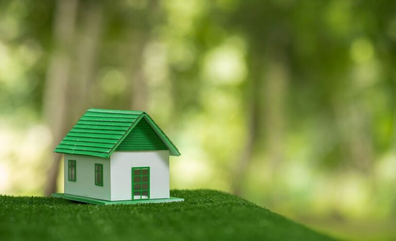 Przyjazny dla środowiska dom nieruchomości. Mały model domu nieruchomości na trawie w zielonej ekologii przyrody. Zrównoważony projekt mieszkaniowy oszczędzający energię i sprzedaż - wynajem koncepcji biznesowej