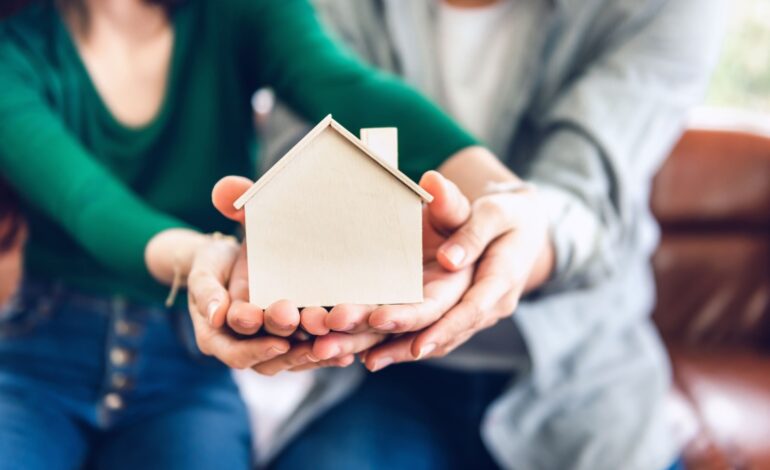 Para trzyma model mieszkaniowy dla przyszłego oszczędzania nieruchomości, ludzie wspólnie chronią nieruchomość domową. Ubezpieczenie domu i koncepcja inwestycji w kredyt mieszkaniowy.