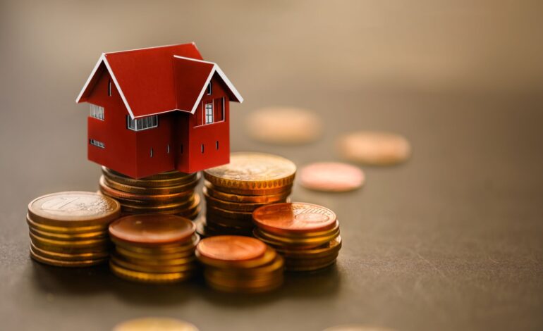 Miniaturowy dom na stosie monet. Pojęcie inwestycji w nieruchomości, pożyczek na nieruchomości, kredytów hipotecznych, podatków