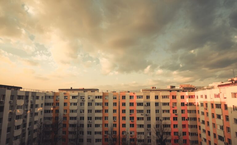 Kolorowy obraz niektórych mieszkań w bloku o zachodzie słońca.
