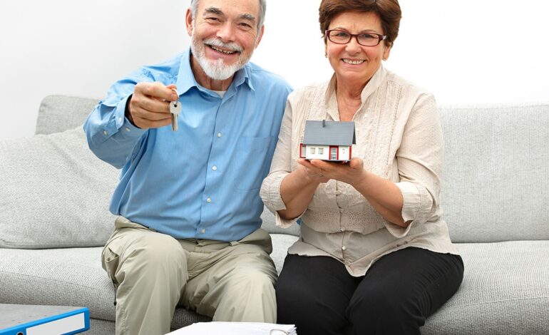Szczęśliwa para seniorów trzymająca mały domek i klucze w rękach