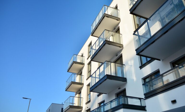 Fasada nowoczesnego apartamentowca w słoneczny dzień. Nowoczesne budynki mieszkalne z ogromnymi oknami i balkonami.